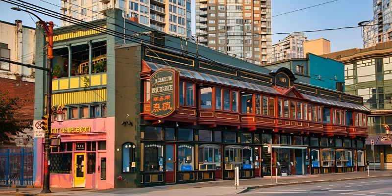 A colorful historic building in Chinatown - Sam Kee Building featuring green and yellow siding, red accents, recessed balconies, and signage displaying Chinese characters.