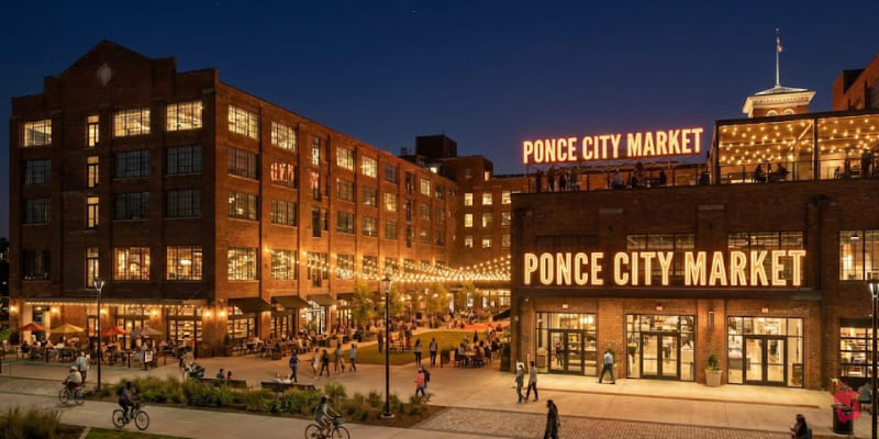 Ponce City Market glows at night with illuminated signage, bustling outdoor areas, and people enjoying the vibrant atmosphere.