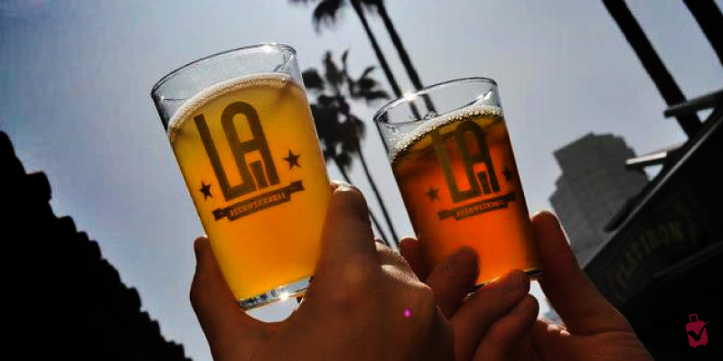 Two perfectly refreshing LA Beer Fest glasses clinking under sunny skies.