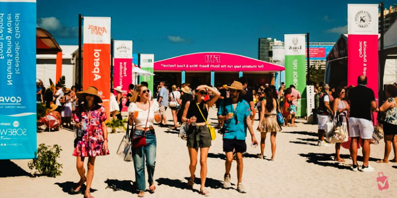 People walk around an outdoor festival with food and drink vendors.