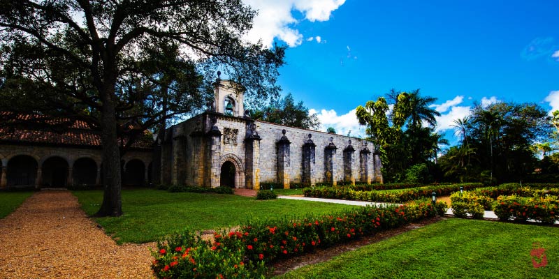 The Ancient Spanish Monastery with green lawns and trees under a blue sky.