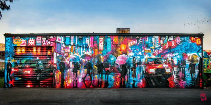 A large mural at Wynwood Walls depicting a nighttime city street with people holding umbrellas in the rain.