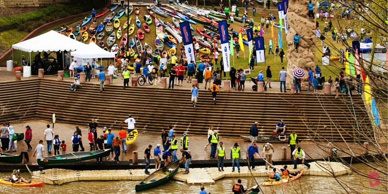 A large crowd gathers along the riverbank for the Buffalo Bayou Regatta with hundreds of colorful kayaks and canoes ready for the race.