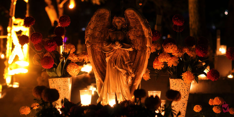 An angel statue surrounded by glowing candles and traditional marigold flowers at the Calaverandia theme park in Guadalajara.
