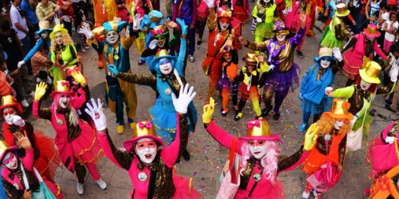 People wearing colorful, eccentric costumes and masks dance through the streets during the lively Desfile de los Locos parade in Guadalajara.