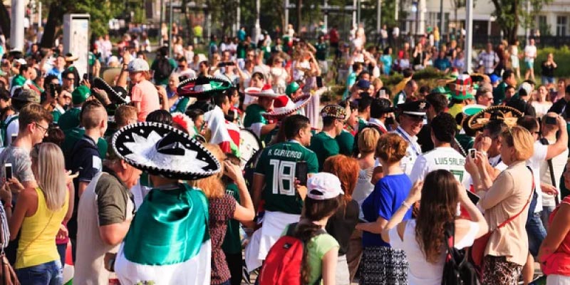 A dense crowd of people, many wearing green and white or sombreros, celebrate at the FIFA Fan Festival in Monterrey.