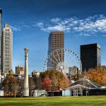 Centennial Olympic Park features a scenic view of the Atlanta skyline and the SkyView Ferris wheel across a sprawling green lawn.