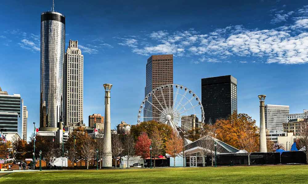 Centennial Olympic Park features a scenic view of the Atlanta skyline and the SkyView Ferris wheel across a sprawling green lawn.