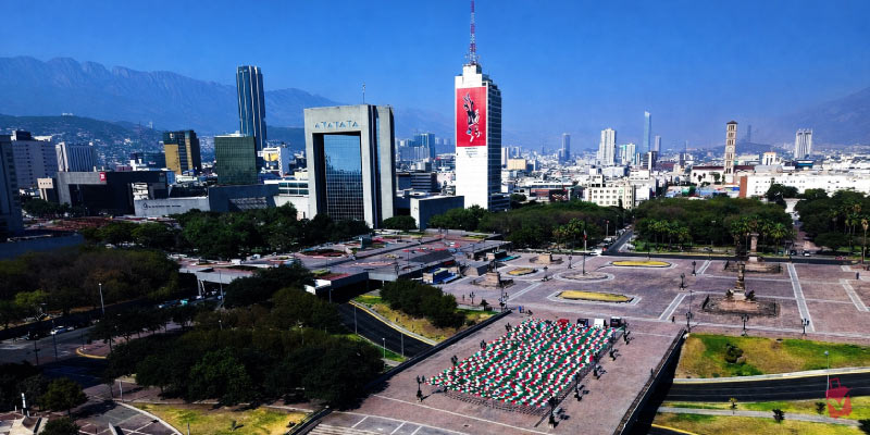 Aerial view of the Macroplaza in Monterrey, Mexico, showing the city skyline and mountains in the background.