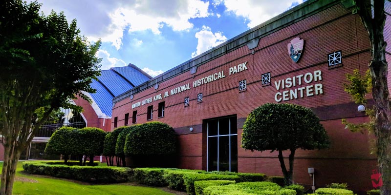 The Visitor Center at the Martin Luther King, Jr. National Historical Park displays a red brick exterior among manicured green hedges.