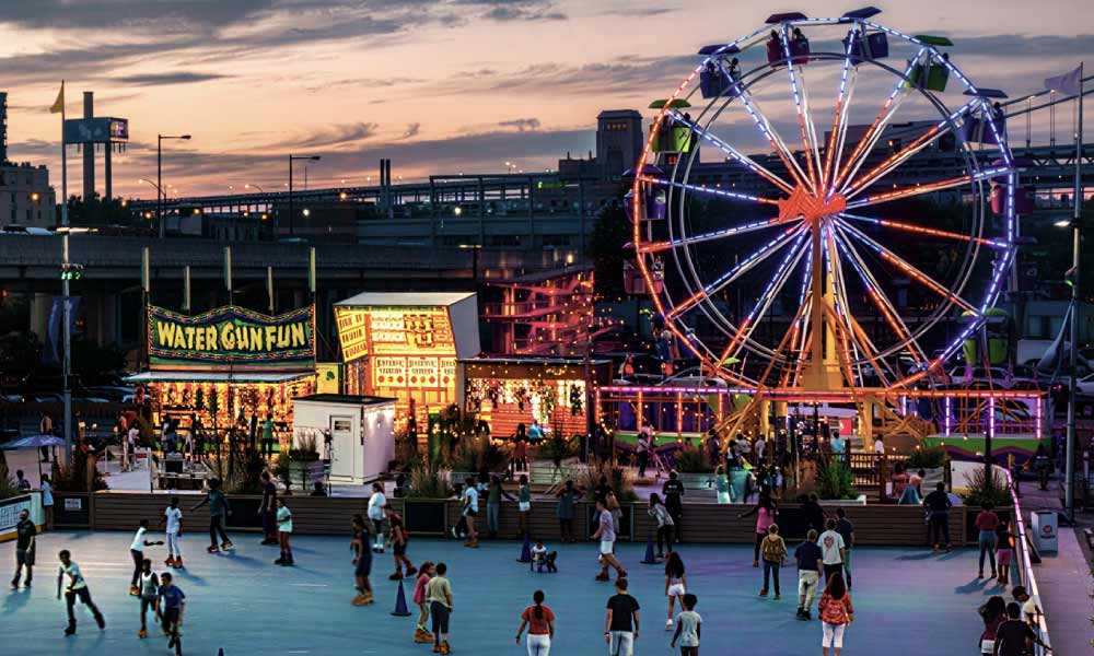 People roller skate at a lively evening carnival with a glowing Ferris wheel during the Most Hyped festivals and events in Houston this year.