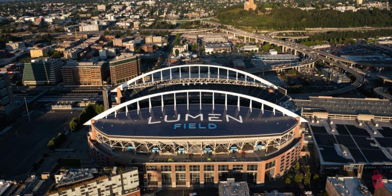 An aerial view of the iconic Lumen Field at sunset, a major Seattle stadium located in the SoDo neighborhood near downtown and Puget Sound.