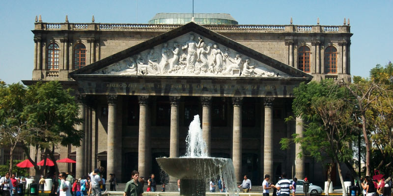 The impressive facade of Teatro Degollado in Guadalajara, featuring a classical design with columns, a sculpted pediment, and a fountain.