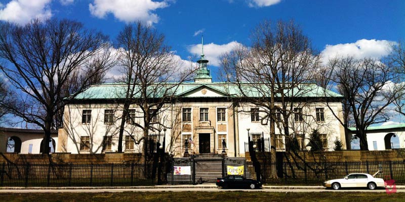 The American Swedish Historical Museum stands prominently with its white facade and distinct green copper roof under a blue sky.