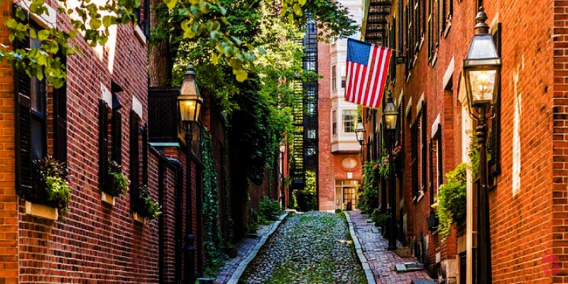 Cobblestone streets and historic brick townhomes with an American flag illustrate the residential history found along The black heritage trail in Boston.
