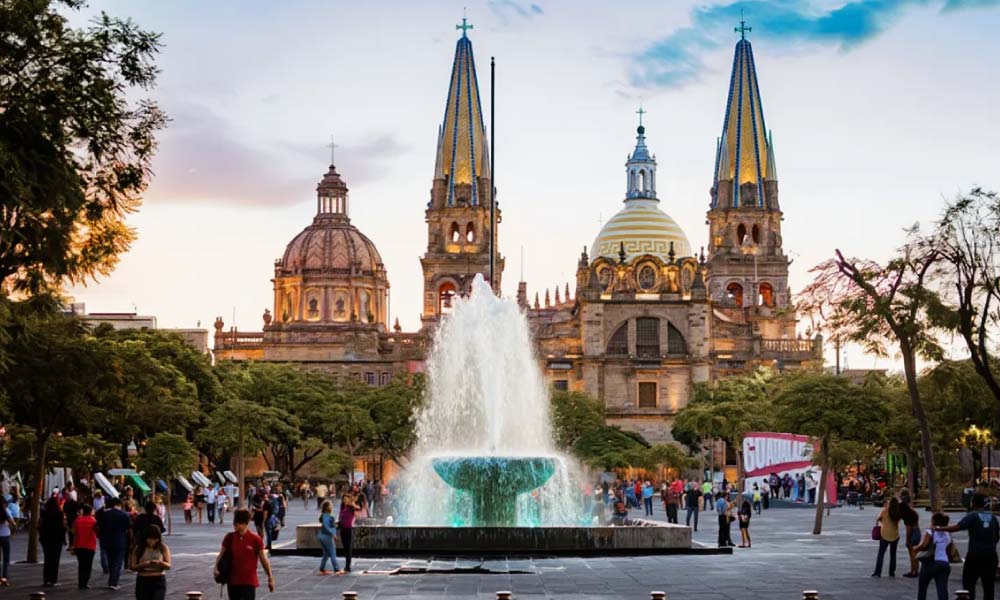 A lively scene in Guadalajara with a fountain in the foreground and the majestic Guadalajara Cathedral in the background, surrounded by people enjoying the area.