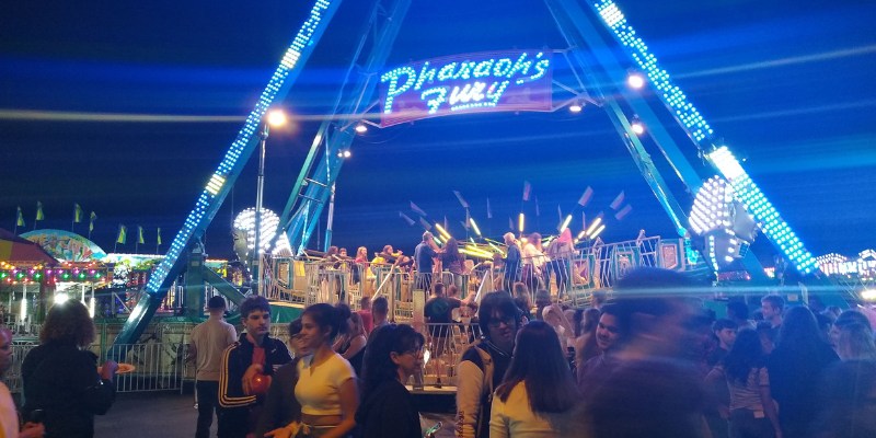 Crowds of people enjoy a brightly lit carnival ride at night during the annual Cape Coral Coconut Festival celebration.
